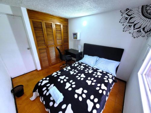 een slaapkamer met een zwart-wit bed en een bureau bij Lovely private room in apartment in Cedritos in Bogota
