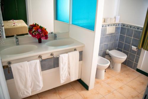 a bathroom with a sink and a toilet at VOI Vila do Farol Resort in Santa Maria