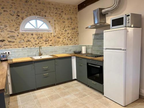 a kitchen with green cabinets and a white refrigerator at Gîte de L'Oliviade - Campagne & Confort in Billancelles