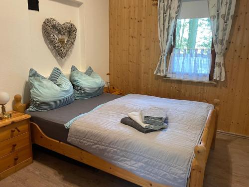 a bedroom with a bed with blue pillows and a heart on the wall at Gemütliches Ferienhaus mit Kamin in idyllischer Waldrandlage 