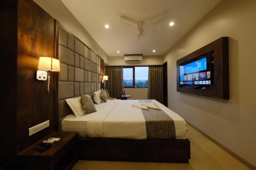 a hotel room with a bed and a television at Nova Candolim By Sudhanand, Candolim in Candolim