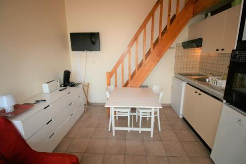 une cuisine avec une table blanche et des armoires blanches dans l'établissement Studio, secteur le Phare, à La Tranche-sur-Mer