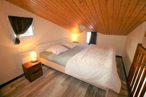 - une chambre avec un lit blanc et un plafond en bois dans l'établissement Studio, secteur le Phare, à La Tranche-sur-Mer