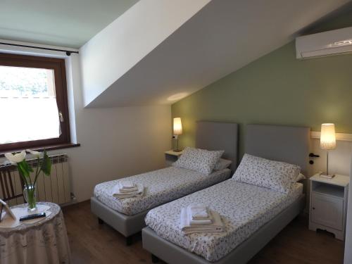 two beds in a small room with a window at La casa di Clara in Esine
