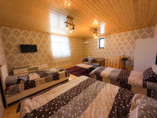 een kamer met 3 bedden en een woonkamer bij Eldeniz Nuxa House in Sheki
