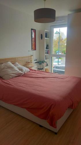 - une chambre avec un lit doté de draps rouges et une fenêtre dans l'établissement T2 neuf au pied de la plage, à Saint-Pierre-Quiberon