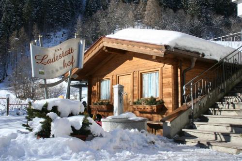 a log cabin in the snow with a sign at Ladestatthof in Neustift im Stubaital
