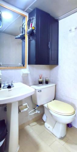een badkamer met een toilet, een wastafel en blauwe kasten bij Lovely private room in apartment in Cedritos in Bogota