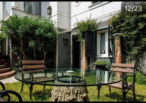 a glass table and two benches in a yard at Casa Rubinacci in Naples