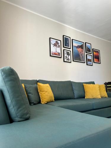 un sofá azul en una sala de estar con fotos en la pared en Eri Apartments, en Shëngjin