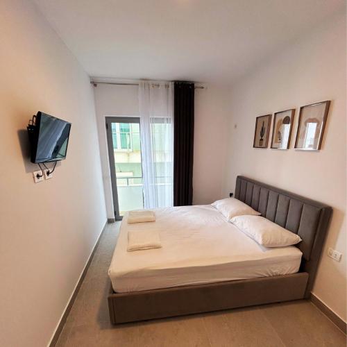 a bedroom with a bed with a tv on the wall at Rana Hedhun Apartment in Margjonaj