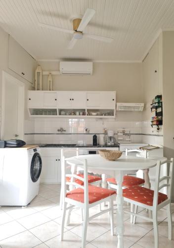 eine weiße Küche mit einem weißen Tisch und Stühlen in der Unterkunft Paralia Nest in Kalamata