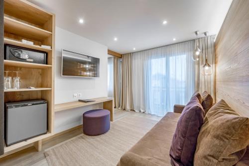 a living room with a couch and a tv at Chalet Silvretta Hotel & Spa in Samnaun