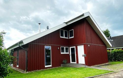 a red barn with a white door and windows at Ferienhaus am See, (1-7 Pers.) Tretboot, Sauna, Whirlpool, Kamin, Kinderspieleparadies in Twist