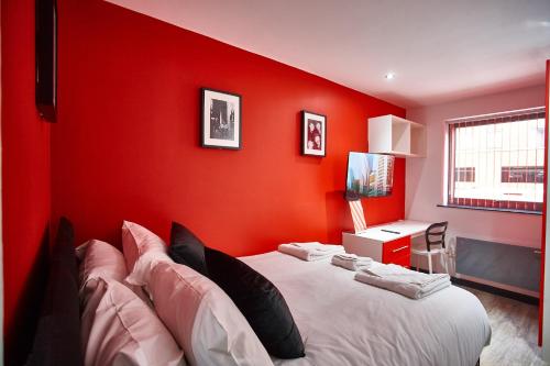 MCCARTNEY SUITE 5 BEDS في ليفربول: غرفة نوم بحائط احمر مع سرير ومكتب