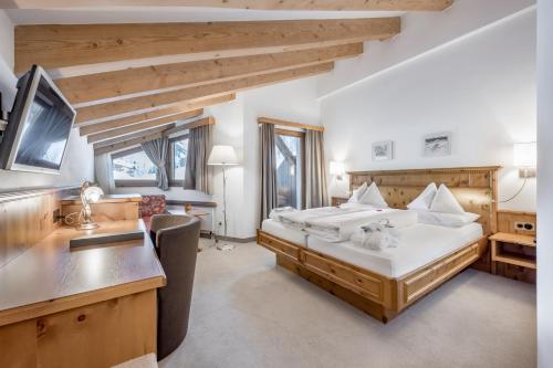 a bedroom with a bed and a desk in a room at Chalet Silvretta Hotel & Spa in Samnaun