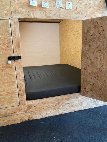 德勒斯登的住宿－FOX BOX II Capsule Apt，一张位于木制盒子里的床铺,配有黑色床垫