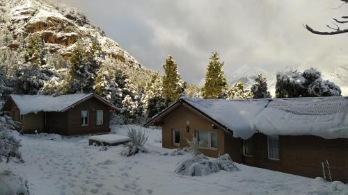 una cabaña en la nieve con una montaña en Cabañas del Gutiérrez en San Carlos de Bariloche
