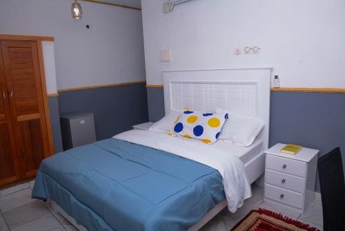 - une chambre bleue et blanche avec un lit et une table de chevet dans l'établissement Ajieh Rest House, à Douala