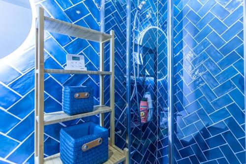 une salle de bain carrelée bleue avec une douche avec des paniers bleus dans l'établissement At Place Bastille near Metro and Maris Modern Comfort in the Heart of Parisian History, à Paris