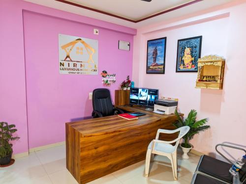an office with a wooden desk and pink walls at Nirmal Luxury Rooms in Garudeshwar