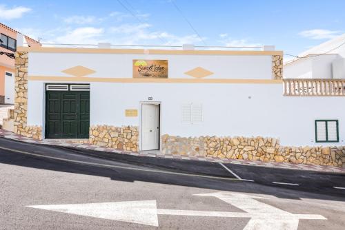 a white building with green doors on a street at sunset lodge in Las Manchas