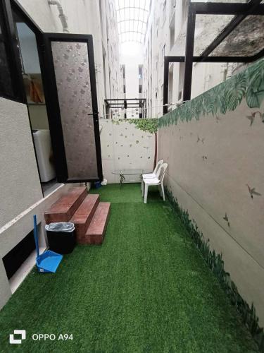 a balcony with a green floor with a bench and chairs at One Oasis Davao Condo 2BR Behind SM Mall with WIFI & Pool in Davao City