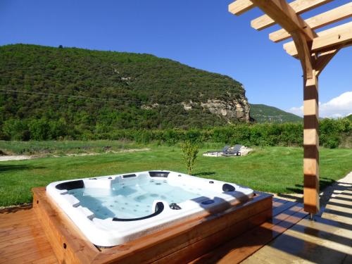 a hot tub on a deck with a view of a mountain at Camin'hôtes Gîte Spa Drôme Lavande in Béconne