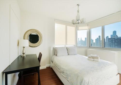 a bedroom with a bed and a desk and a window at Stylish 3BR Apartment At Midtown East in New York