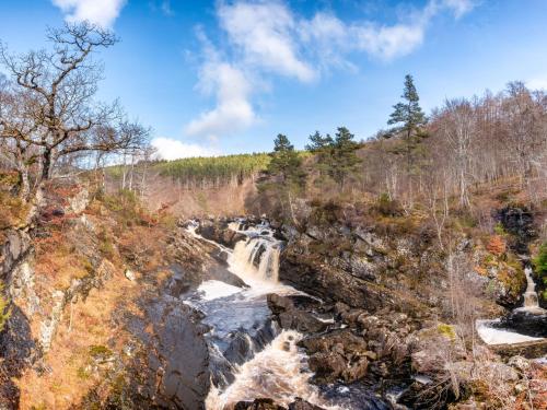 a waterfall on the side of a mountain with trees at Holiday Home Dancot by Interhome in Invermoriston