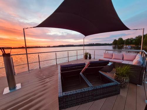 a boat deck with a couch and a sunset at Seezeit- Schwielochsee- Hausboot in Schwielochsee