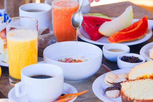 a table topped with plates of breakfast foods and drinks at VELINN Hotel Fazenda Fonte das Hortênsias in Santo Antônio do Pinhal