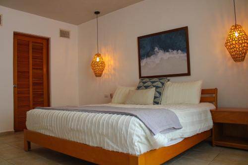 a bedroom with a large bed with two lights on it at Villas Mayaluum Cozumel in Cozumel
