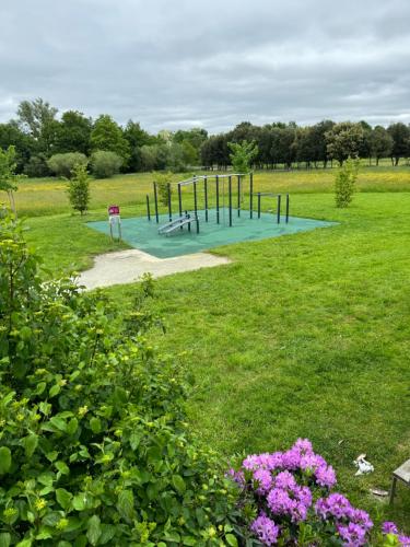 un parque infantil en un campo con un parque con flores en Au calme de la Gaité en Saint-Jacques-de-la-Lande