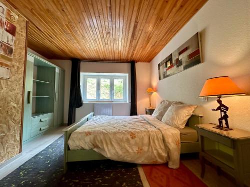 a bedroom with a bed and a wooden ceiling at Le Val Thibaud in Buncey
