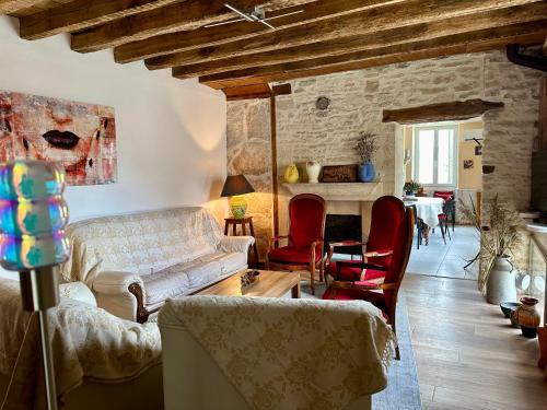 a living room with a white couch and red chairs at Le Val Thibaud in Buncey