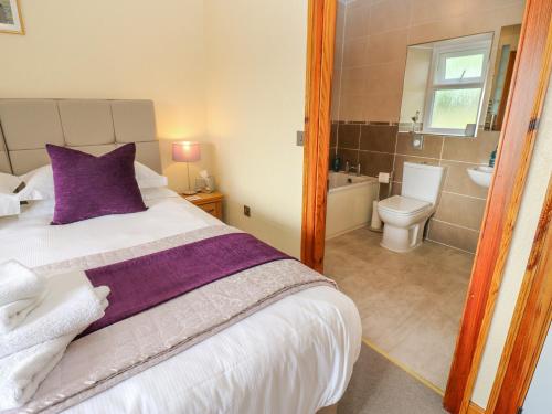 a bedroom with a large bed and a bathroom at Longwell House in Grayrigg
