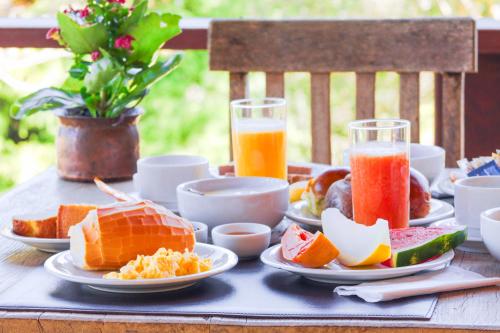 una mesa con platos de comida y dos vasos de zumo de naranja en VELINN Hotel Fazenda Fonte das Hortênsias en Santo Antônio do Pinhal