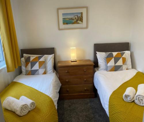 a bedroom with two beds and a night stand with towels at Claire’s place in Hayle