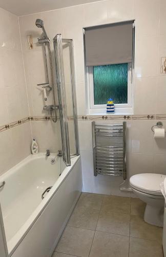 a bathroom with a tub and a toilet and a window at Claire’s place in Hayle