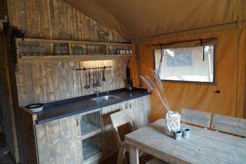 a kitchen with a sink and a table in a trailer at Luxe en romantische overnachting voor 2 in Behelp
