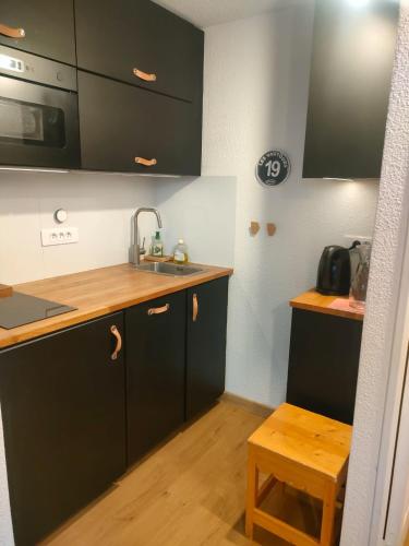 - une cuisine avec des placards noirs et un évier dans l'établissement Duplex confort Risoul, à Risoul