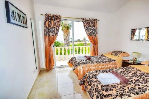 a hotel room with two beds and a window at Villa Ambrosia in Peyia