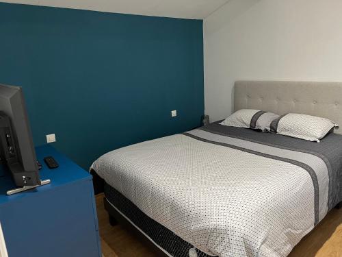 une chambre avec un lit et un mur bleu dans l'établissement La maison de Kelenn, à Saint-Martin-de-Laye