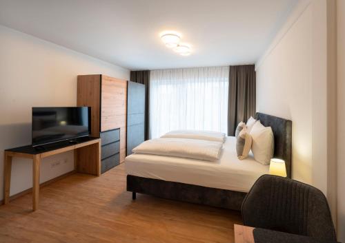 een slaapkamer met een bed en een flatscreen-tv bij das windsHEIM Appartements by Vital Hotel in Bad Windsheim