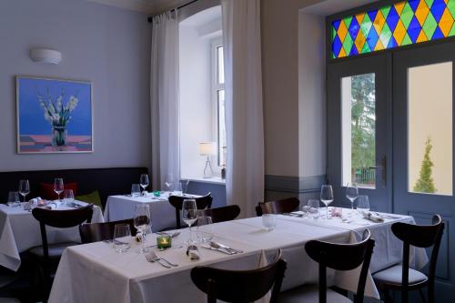 um restaurante com mesas e cadeiras brancas e uma janela em Boutique Hotel SwissHouse em Mariánské Lázně