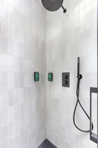La salle de bains est pourvue d'une douche et de murs carrelés blancs. dans l'établissement MyKeypers - Design & Cosy Flat 4P - Paris XV, à Paris