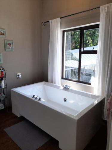 a large white bath tub in a room with a window at Safari Villa Botique Hotel in Windhoek
