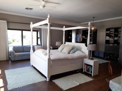 ein Schlafzimmer mit einem weißen Himmelbett und einem Sofa in der Unterkunft Safari Villa Botique Hotel in Windhoek