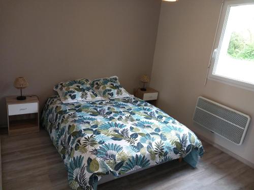 a bedroom with a bed with a blue and white comforter at Maison vacance proche ste mère église in Picauville